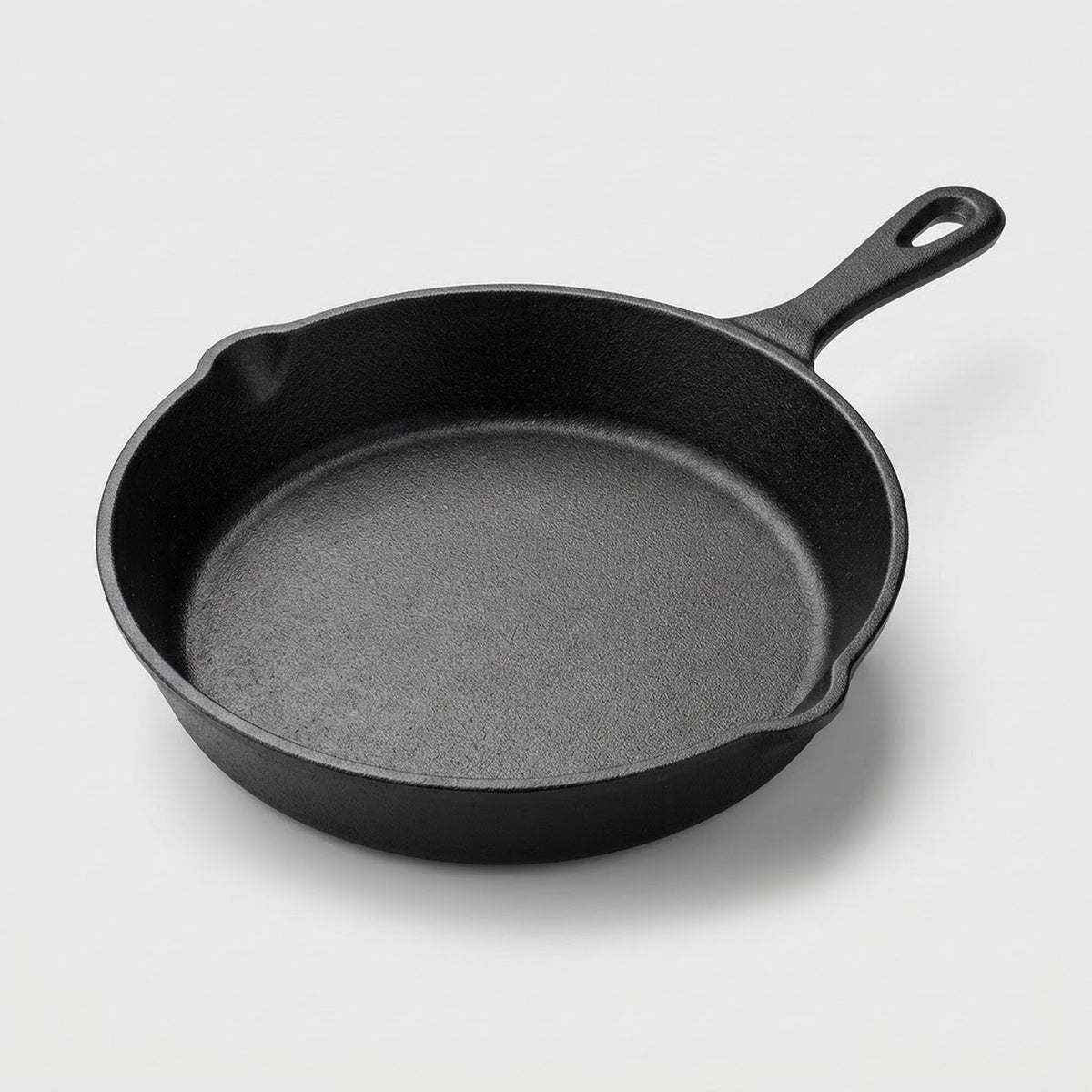 A classic black cast iron skillet with a single loop handle, photographed from a high angle on a light gray background.
