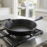 A black cast iron skillet sits on a gas stovetop in a bright kitchen setting.