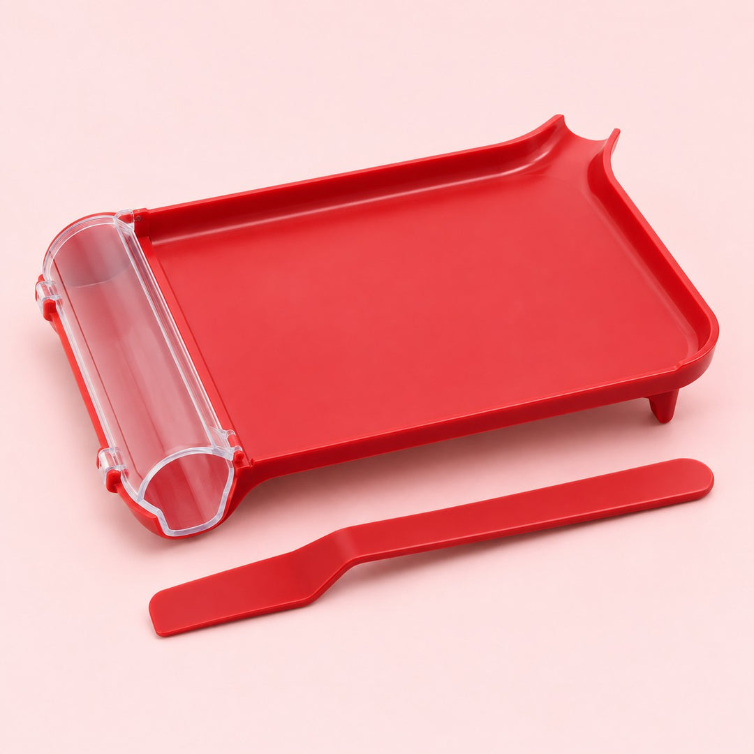 Red plastic pill counting tray with clear chute and matching spatula on a pale blush studio background.