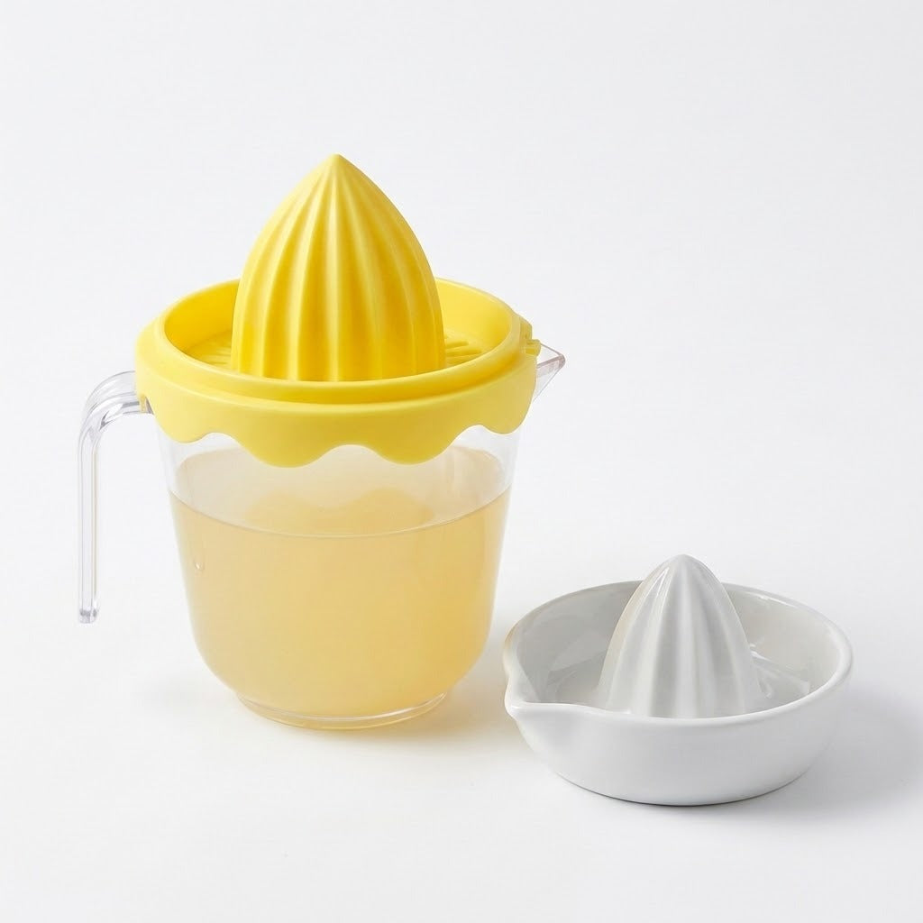 Yellow citrus juicer with a clear cup containing juice stands beside a shallow white citrus reamer against a white background.