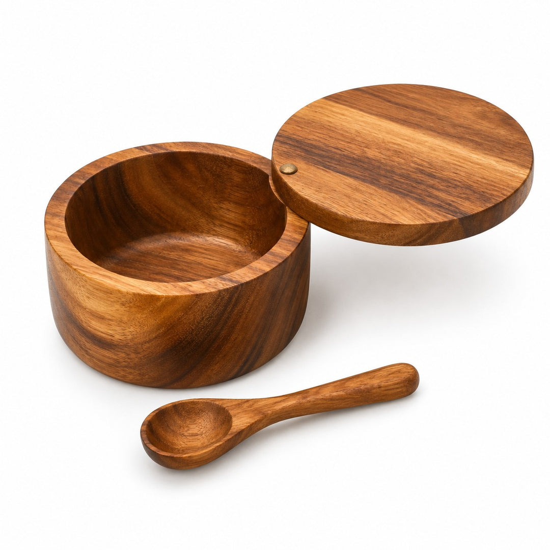 Single bowl acacia wood salt cellar, swivel lid, and matching wooden spoon on white.