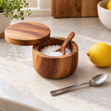 Compact acacia wood salt cellar with spoon sits beside a teaspoon and lemon for scale.