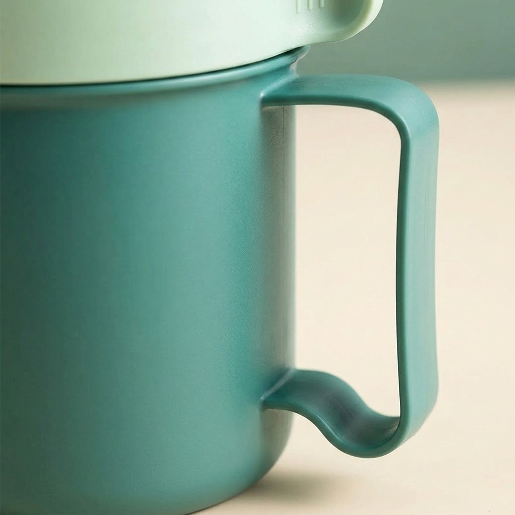 Close-up of a matte teal ceramic mug with a matching handle and a light mint lid, set against a soft beige background.