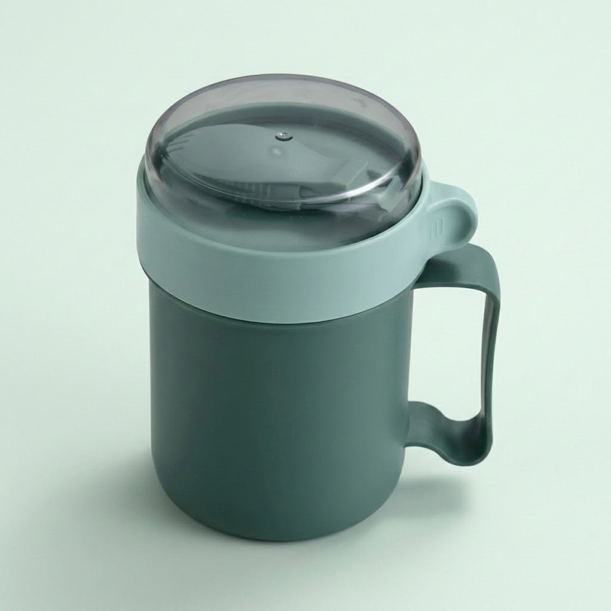 A dark green insulated mug with a matching dark green handle and a translucent dark gray lid, shown on a light green background.