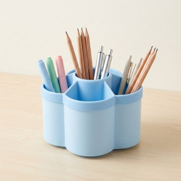 A light blue three-compartment desk organizer holding pens and pencils, set on a light wood tabletop against a cream background.