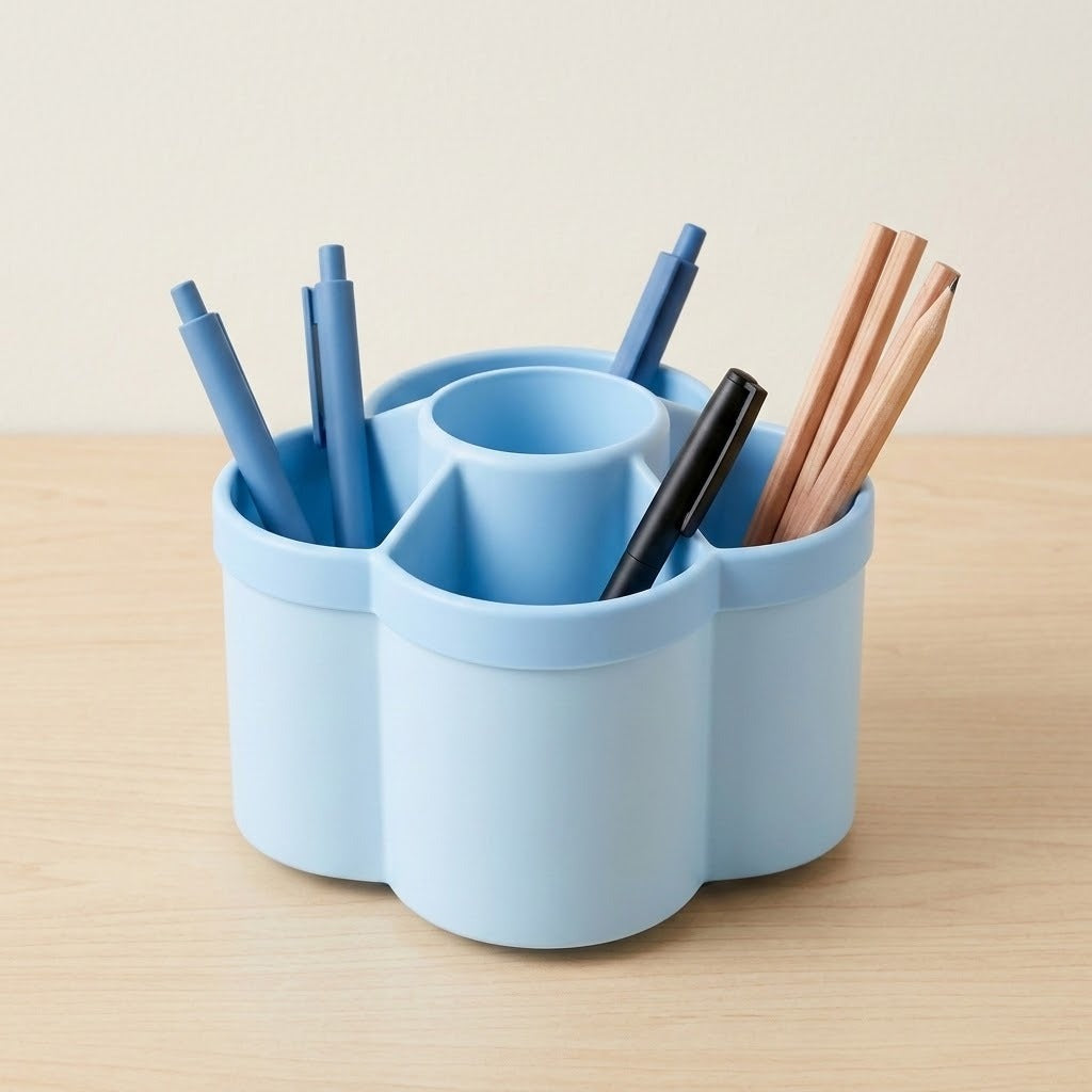 A light blue multi-compartment desk organizer holding pens and chopsticks, set on a light wood tabletop against a neutral beige background.