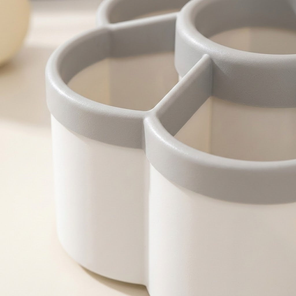 A close-up of a white and light gray multi-compartment cup or organizer with rounded cylindrical sections.