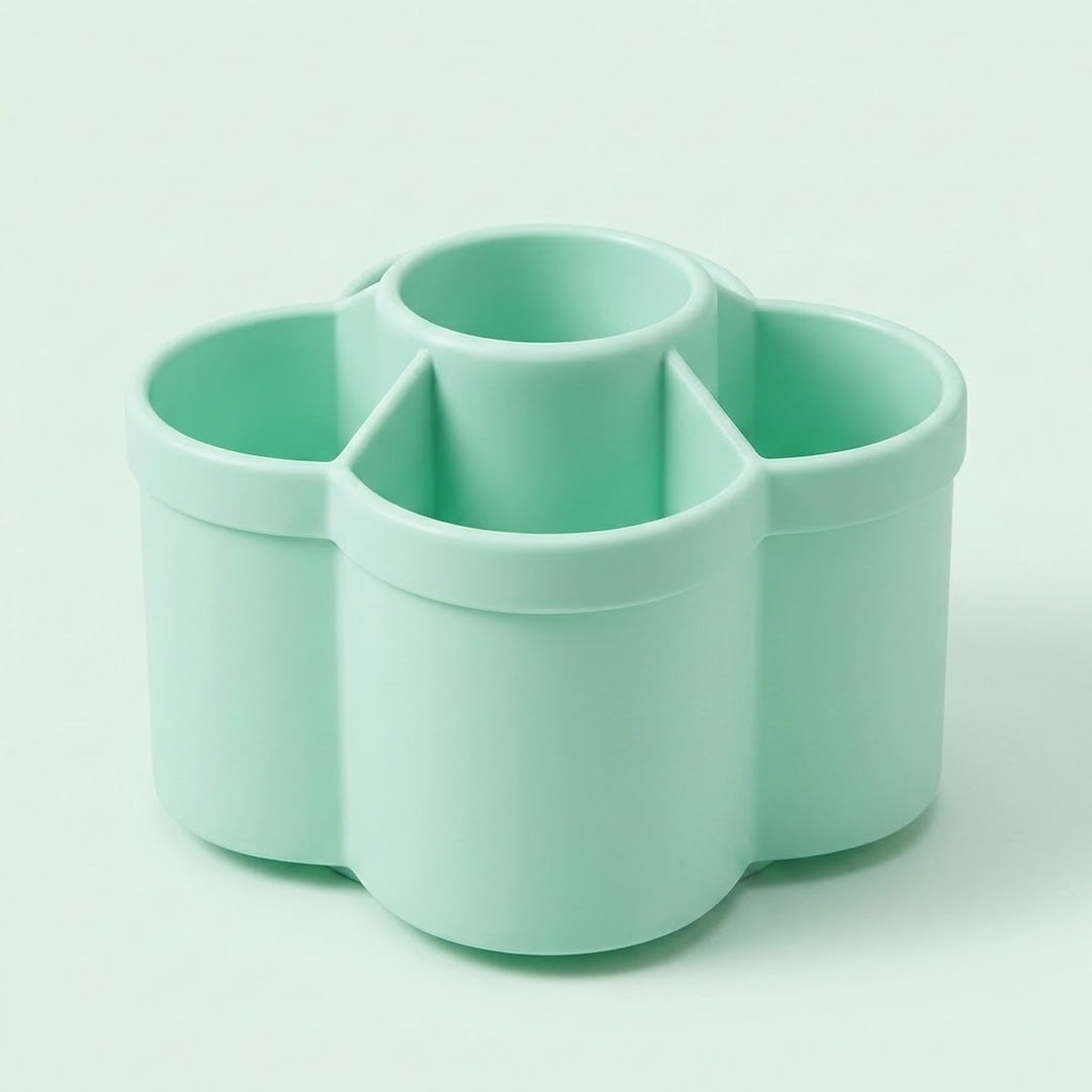 A mint green plastic multi-compartment organizer with four cylindrical cups, shown on a clean, solid, very light mint green background.