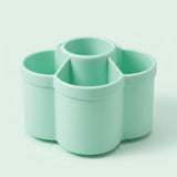 A mint green plastic multi-compartment organizer with four cylindrical cups, shown on a clean, solid, very light mint green background.