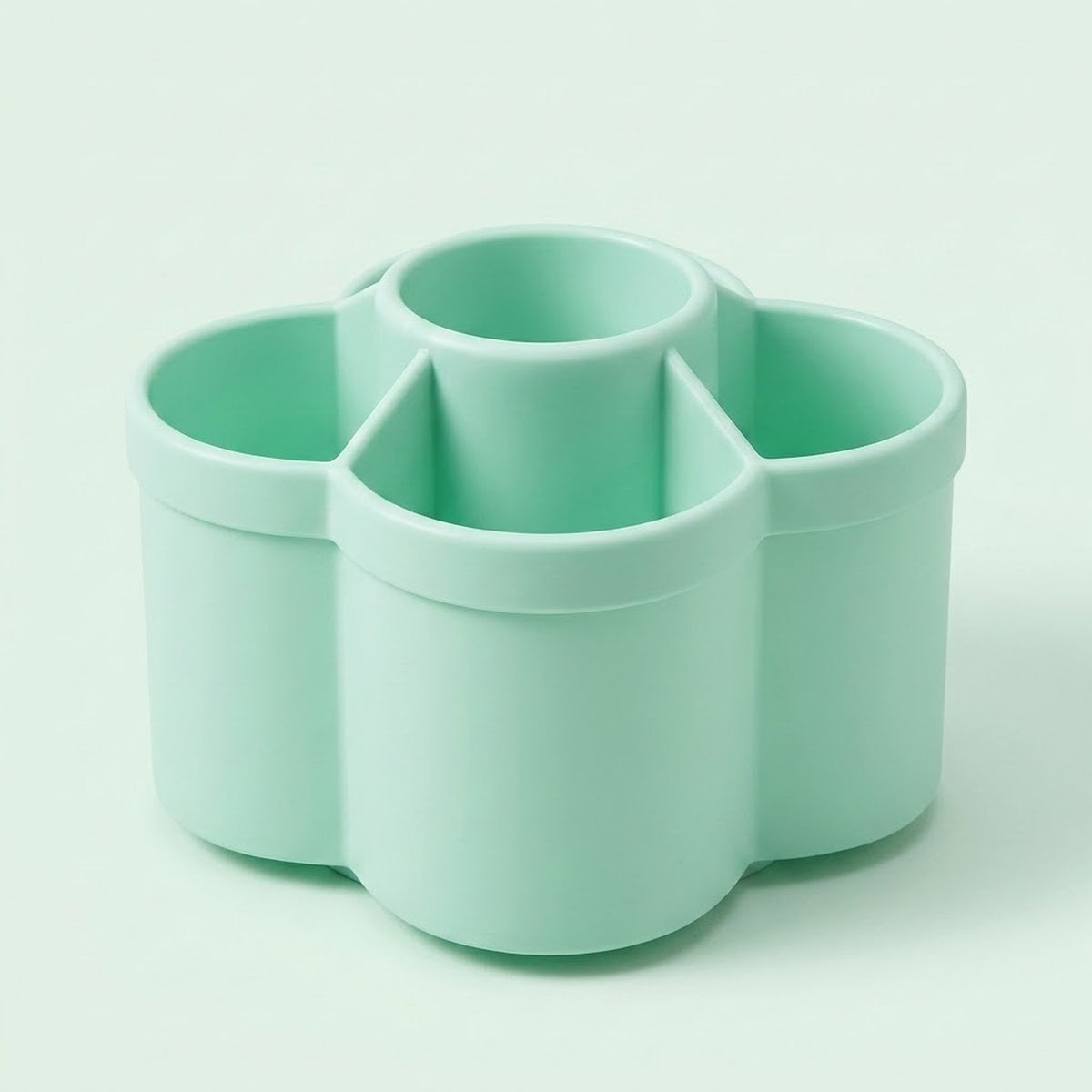 A mint green plastic multi-compartment organizer with four cylindrical cups, shown on a clean, solid, very light mint green background.