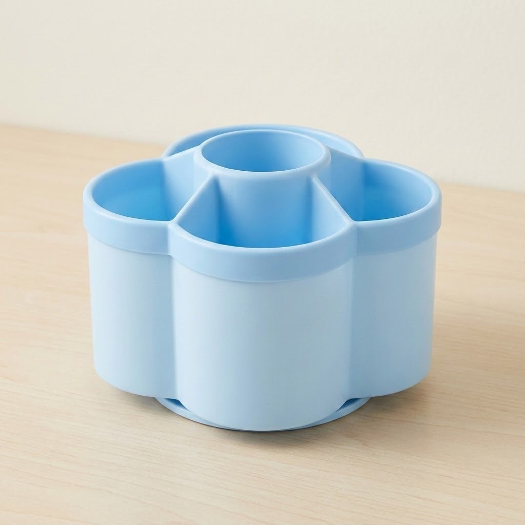 A light blue plastic multi-compartment organizer with a circular base and four cylindrical sections, shown on a light wood surface against a neutral beige background.
