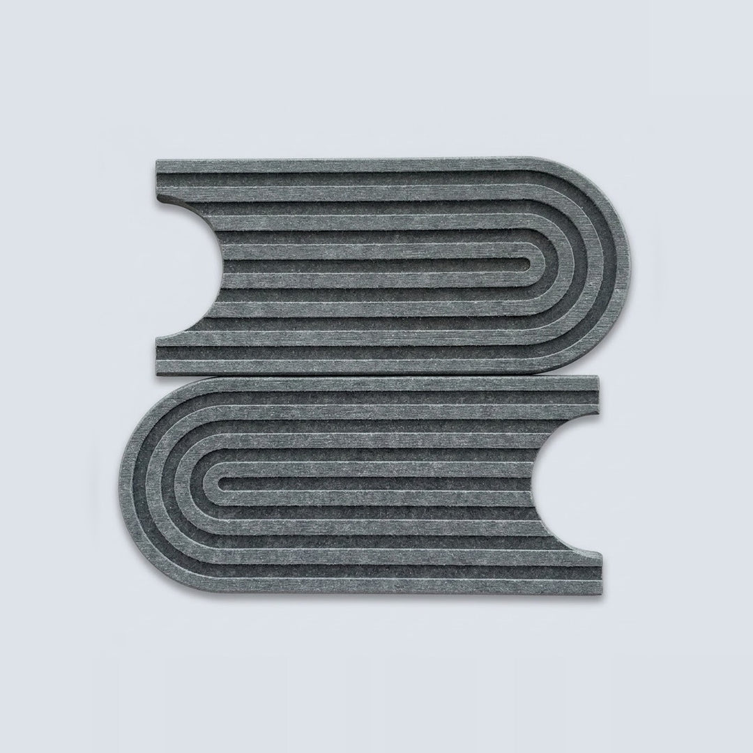 Two gray felt book-shaped mats with concentric curved stripes, displayed on a light gray background.