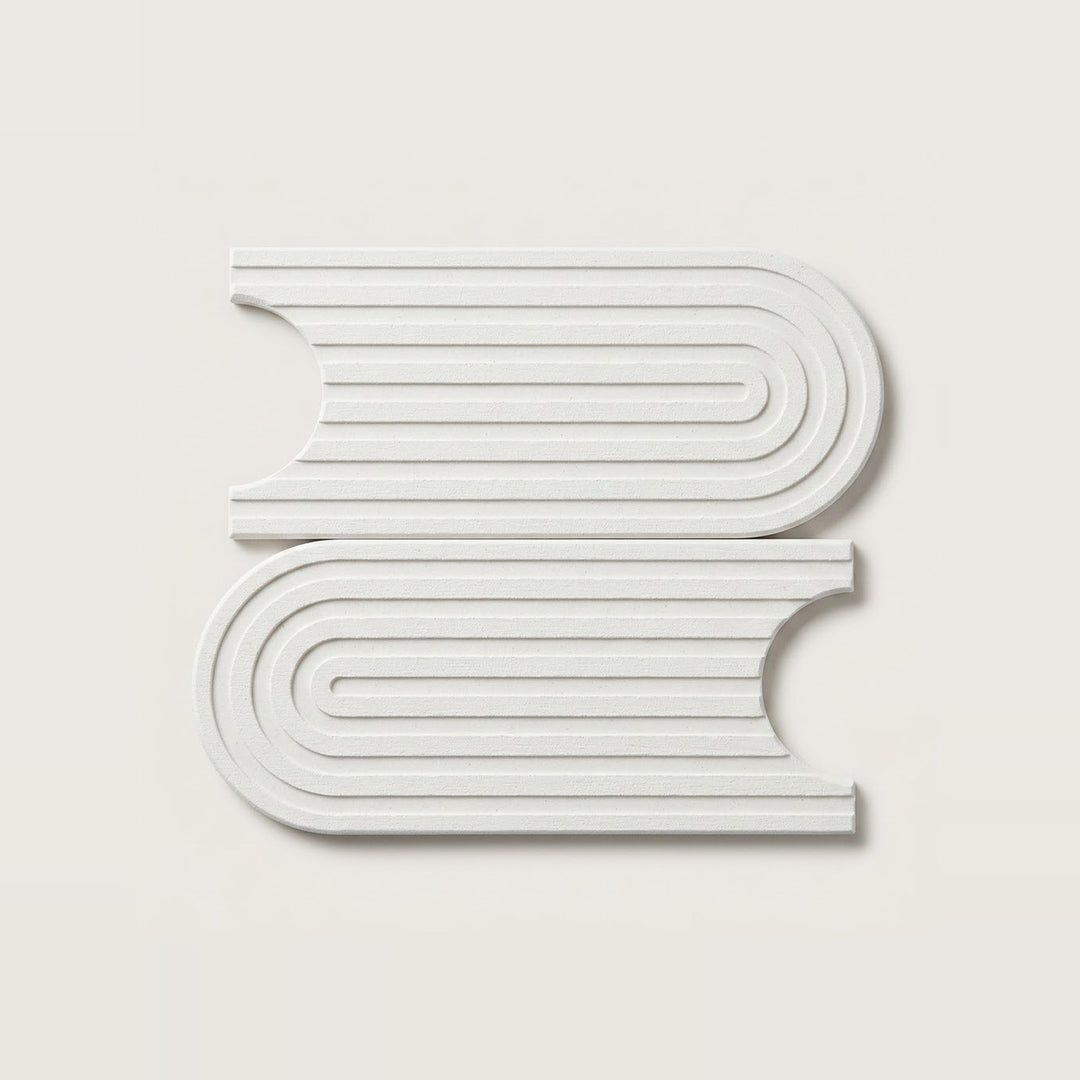 Two white, book-shaped decorative wall art pieces with concentric ridged lines, displayed on a light beige background.