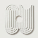 A modern, abstract white wall-mounted sculpture or decorative art piece featuring concentric arches and vertical grooves on a light gray background.