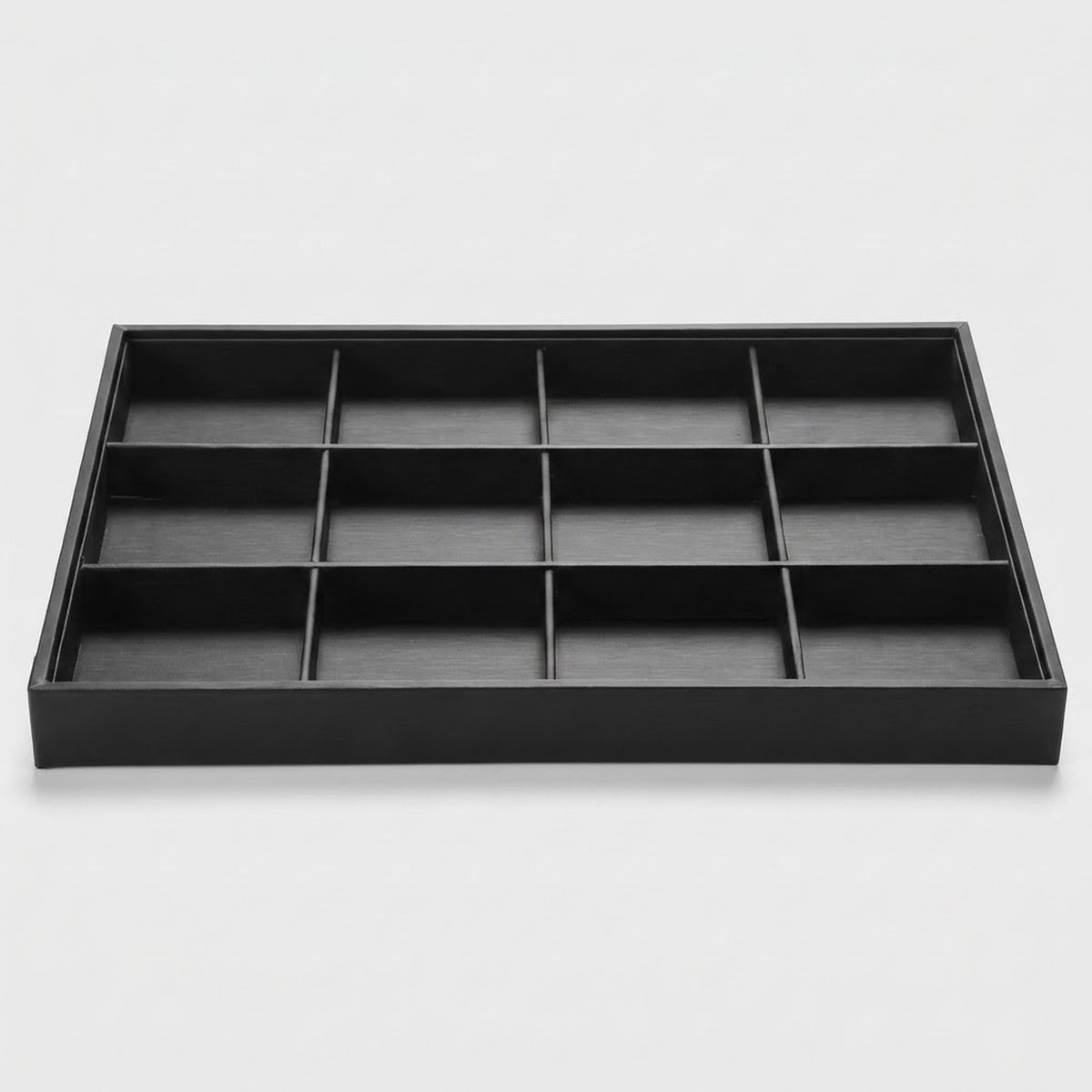 A black rectangular jewelry organizer tray with twelve individual compartments arranged in a 3x4 grid, shown on a light gray background.