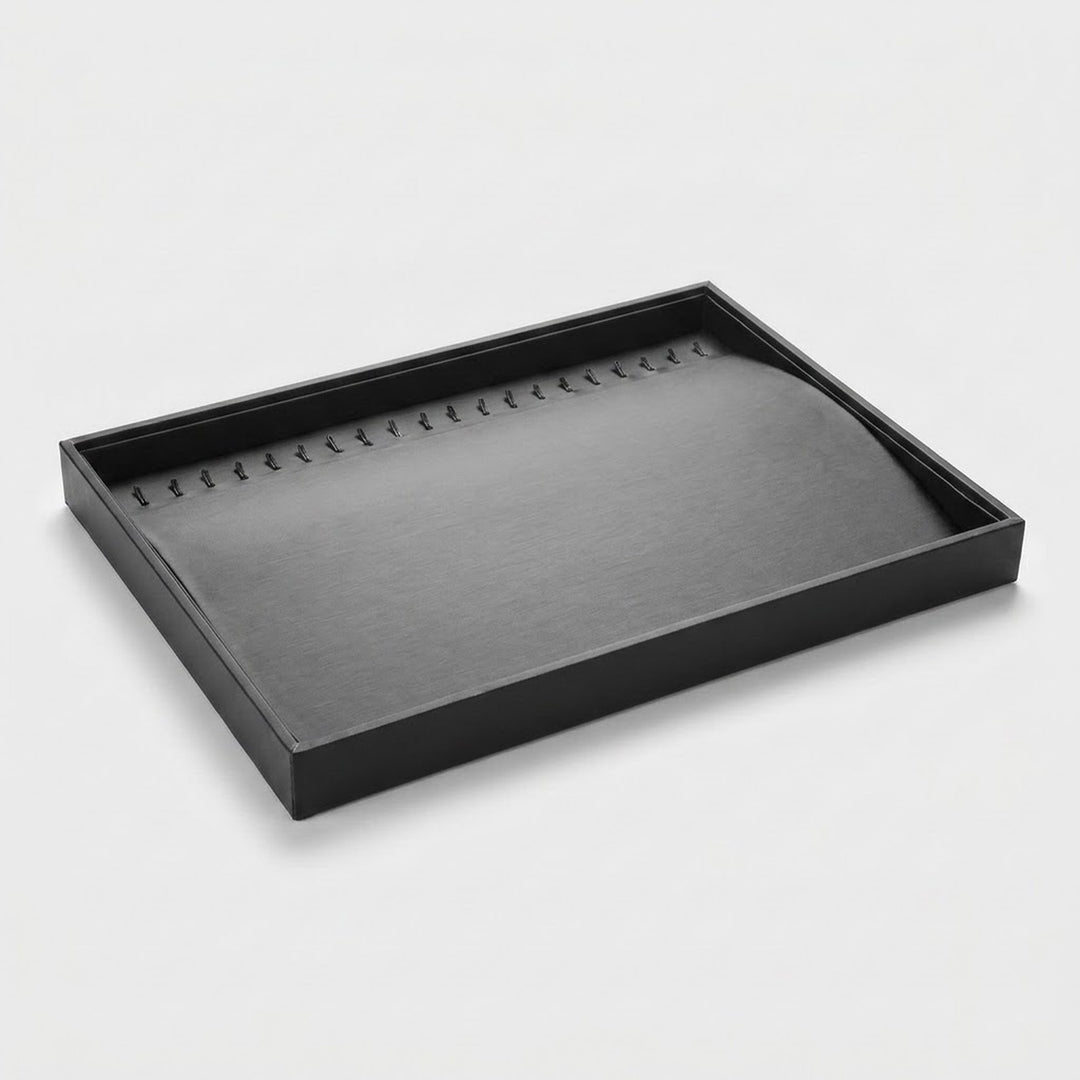 A black rectangular jewelry display tray with a curved, padded interior, photographed on a clean light gray background.