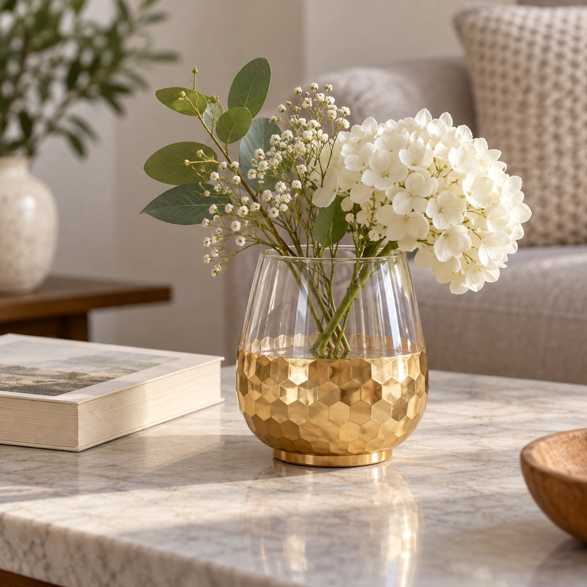 Small Gold Honeycomb Glass Vase sits beside a paperback and flowers to show its tabletop scale.