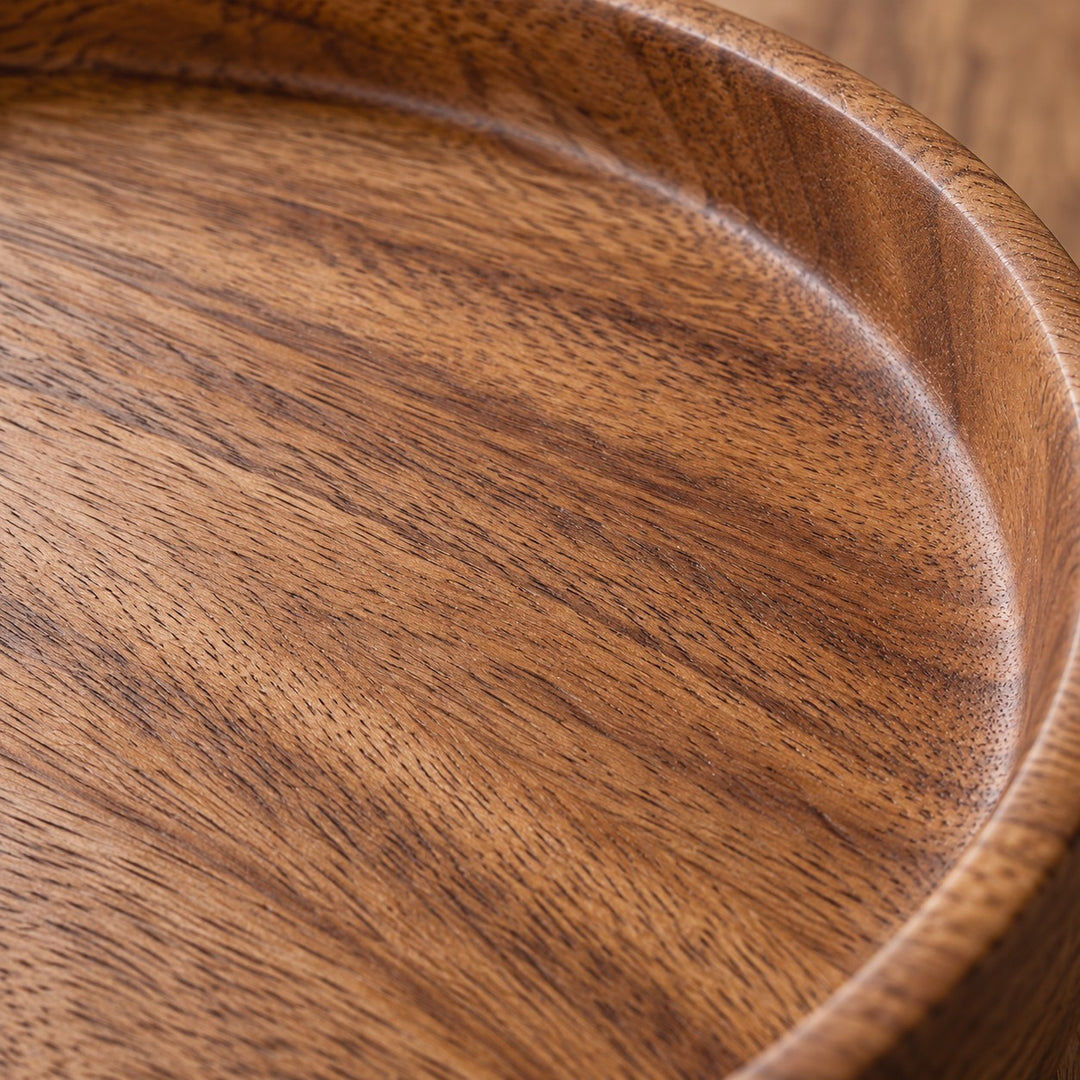 Close-up of the serving tray's warm wood grain, smooth finish, and gently raised circular rim.