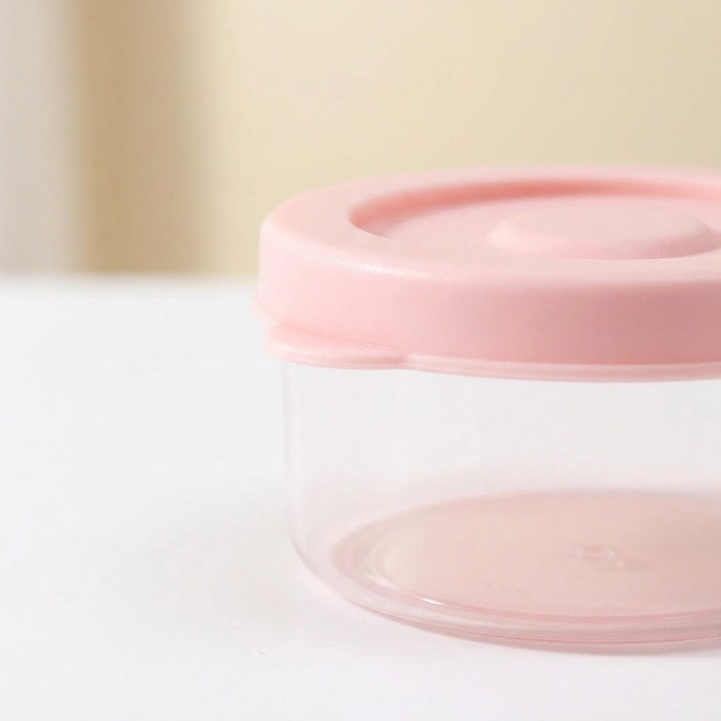 A small clear plastic storage container with a light pink lid, shown on a white surface with a soft beige background.