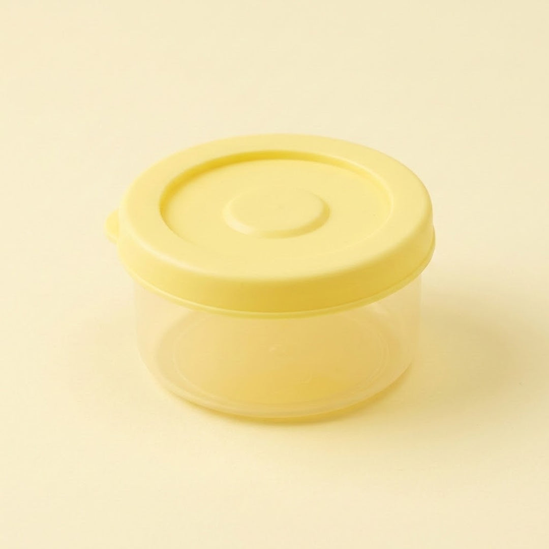 A small round plastic storage container with a translucent yellow lid and a clear body, shown on a plain light beige background.