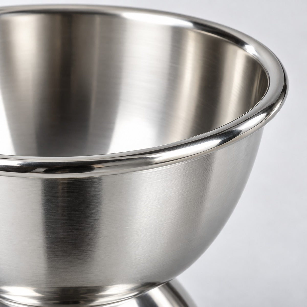 Close-up of the dessert cup showing its smooth reflective stainless steel rim and bowl.