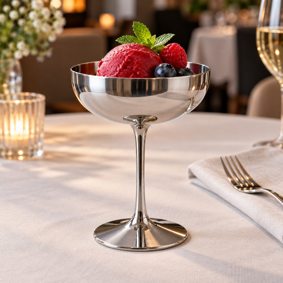 Tall stem stainless steel dessert cup presents sorbet at a softly lit restaurant table.