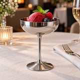 Tall stem stainless steel dessert cup presents sorbet at a softly lit restaurant table.