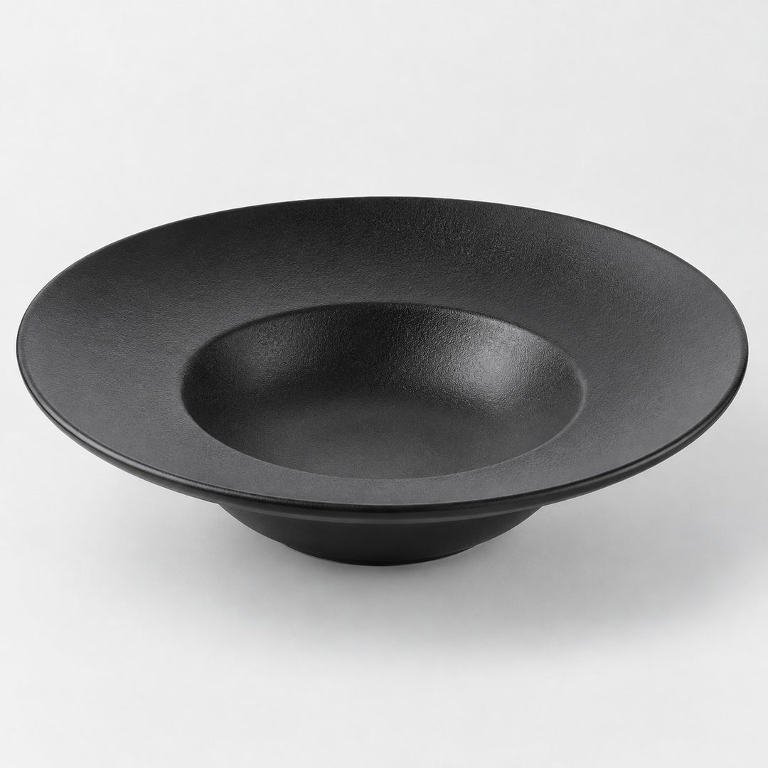 Black deep dish melamine plate with a sloping textured surface and raised bowl-like center on gray.