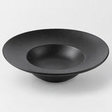 Black deep dish melamine plate with a sloping textured surface and raised bowl-like center on gray.
