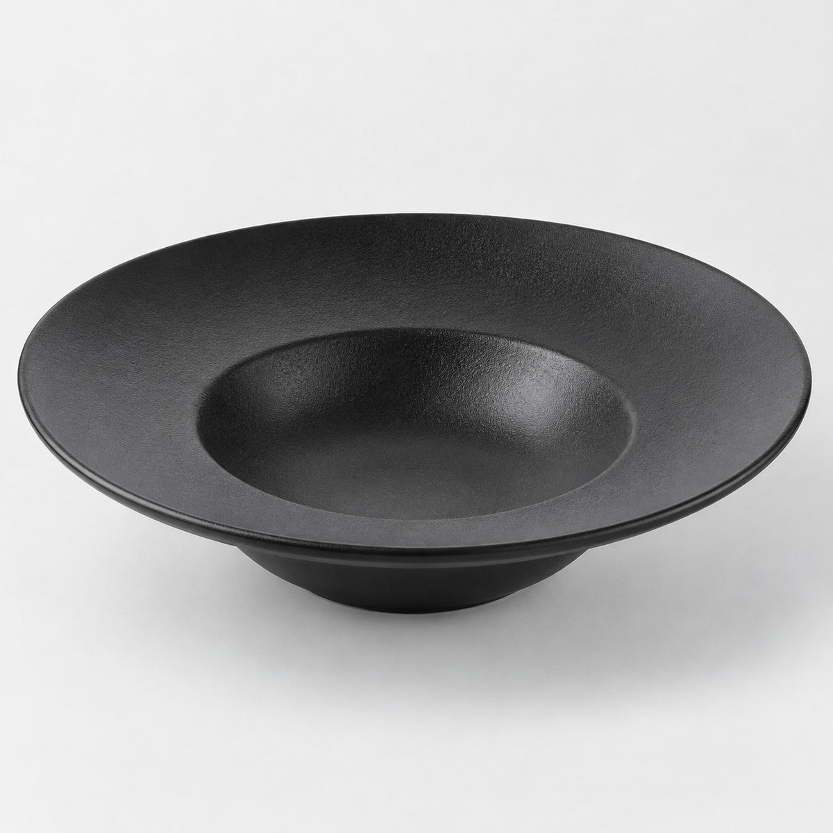 Black deep dish melamine plate with a sloping textured surface and raised bowl-like center on gray.