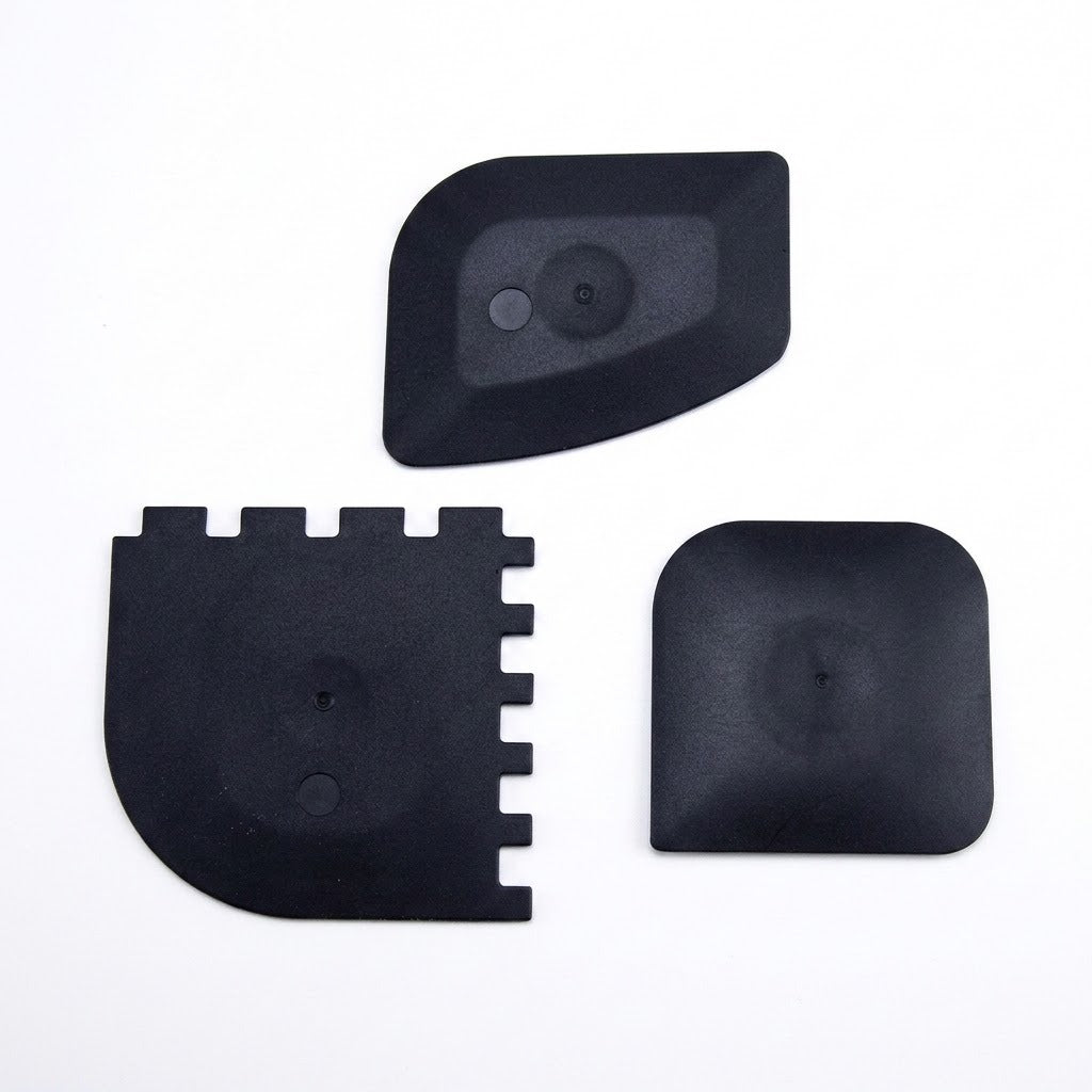Three black plastic replacement parts with different shapes, displayed on a clean white background.