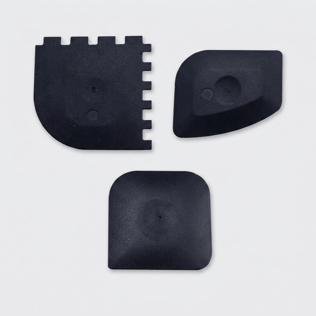 Three black plastic replacement parts with different shapes, displayed on a light gray background.