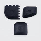 Three black plastic replacement parts with different shapes, displayed on a light gray background.