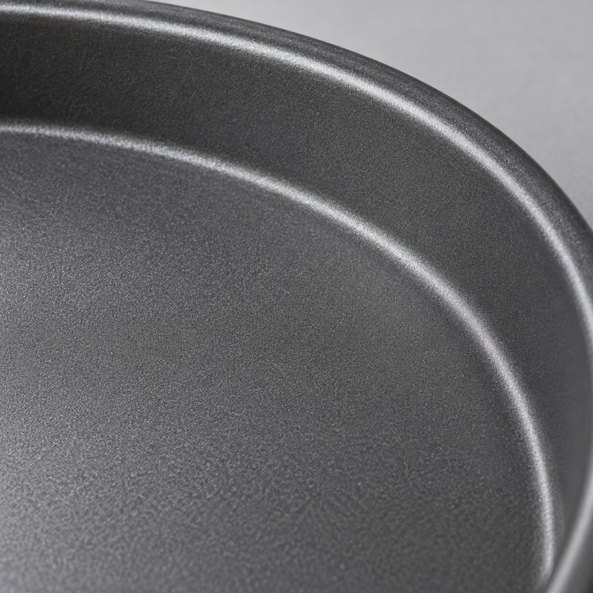 Close view of the pizza pan's fine matte nonstick interior and curved metal rim.