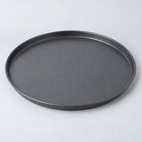 Fourteen inch round charcoal nonstick pizza pan centered on a pale gray studio background.