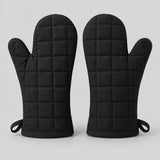 Pair of black quilted cotton blend oven mitts centered on a pale gray studio background.