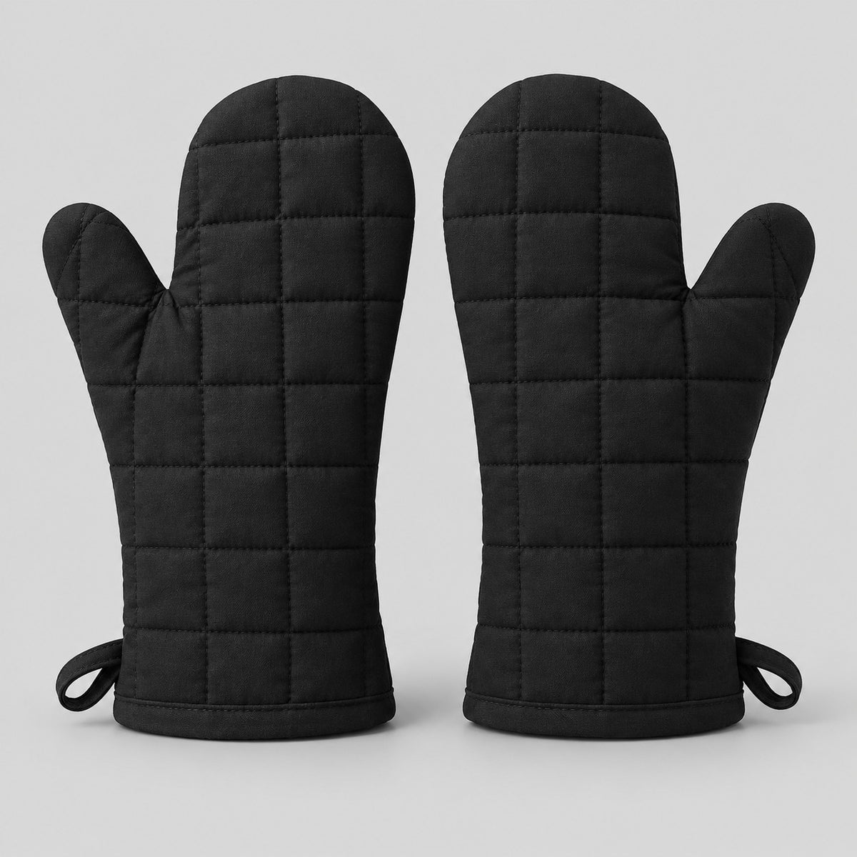 Pair of black quilted cotton blend oven mitts centered on a pale gray studio background.