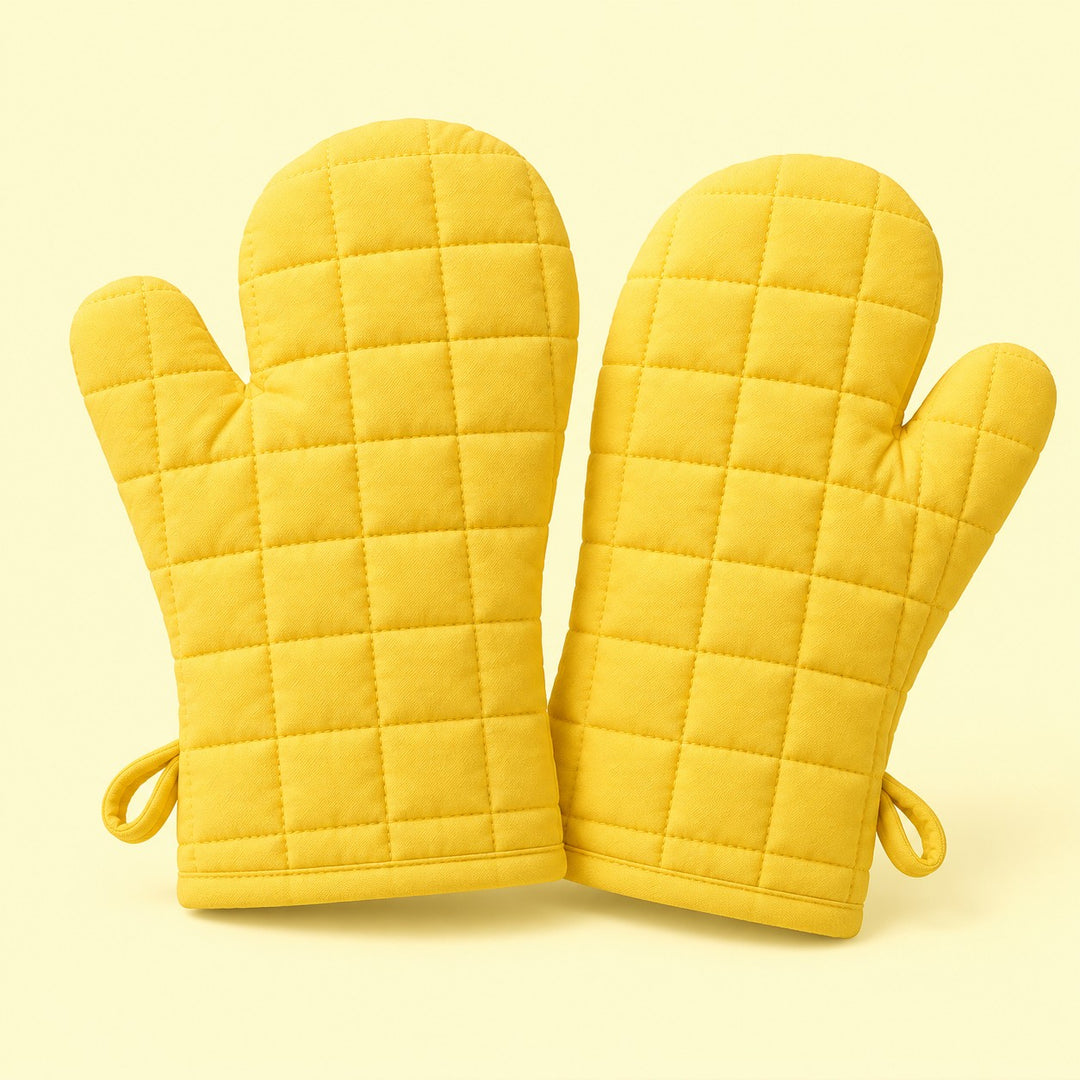 Pair of yellow quilted cotton blend oven mitts centered on a pale yellow studio background.