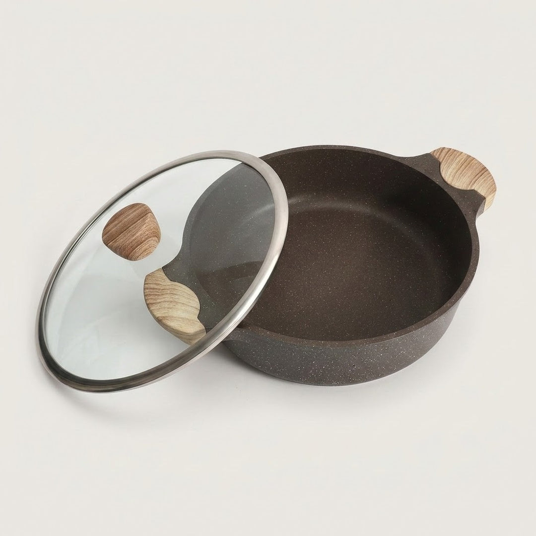 A dark brown speckled non-stick pan with a matching glass lid featuring a silver metal rim and light wood handles, displayed on a clean off-white background.