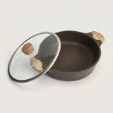 A dark brown speckled non-stick pan with a matching glass lid featuring a silver metal rim and light wood handles, displayed on a clean off-white background.