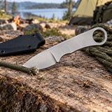 Silver steel fixed blade knife trims a loose cord at a simple campsite work surface.