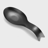 A matte black spoon rest shaped like a stylized spoon, photographed on a clean light gray background.
