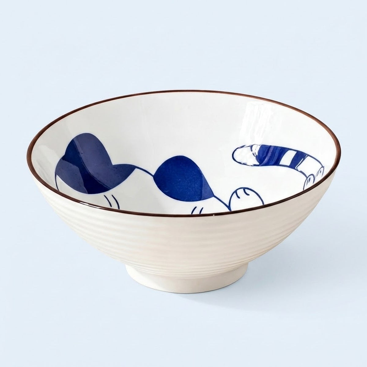 White ceramic bowl with a blue cat illustration inside and a thin brown rim sits against a pale blue background.