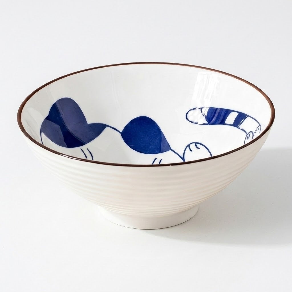 White ceramic bowl with a blue cat illustration and striped tail has a brown rim and ridged exterior against a white background.