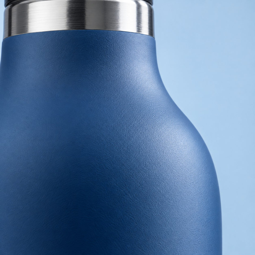 Close detail of the blue bottle's smooth matte coating and reflective stainless steel neck.
