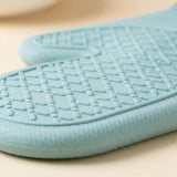 A close-up of a light blue textured non-slip mat with a raised grid pattern, resting on a neutral beige surface.