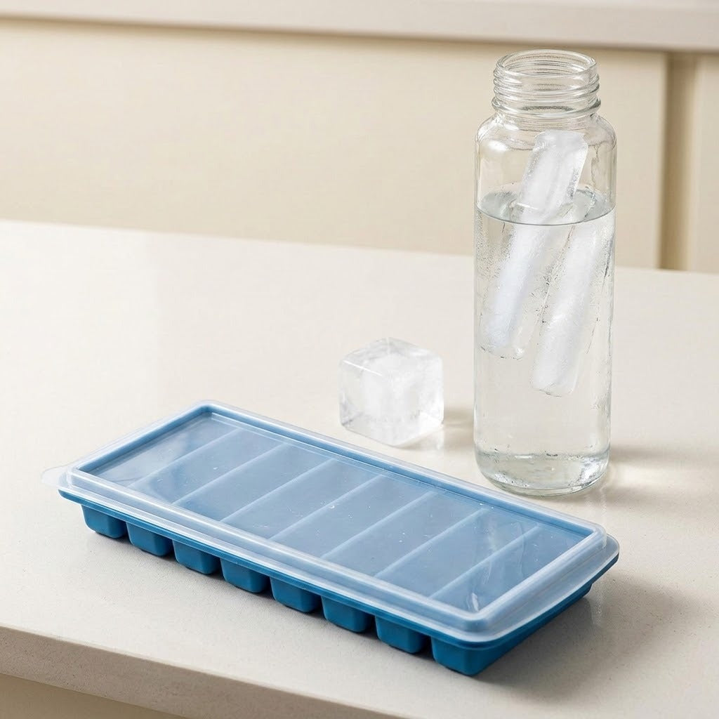 A blue silicone ice cube tray with a clear lid sits on a light beige countertop next to a clear glass bottle filled with water and ice cubes.