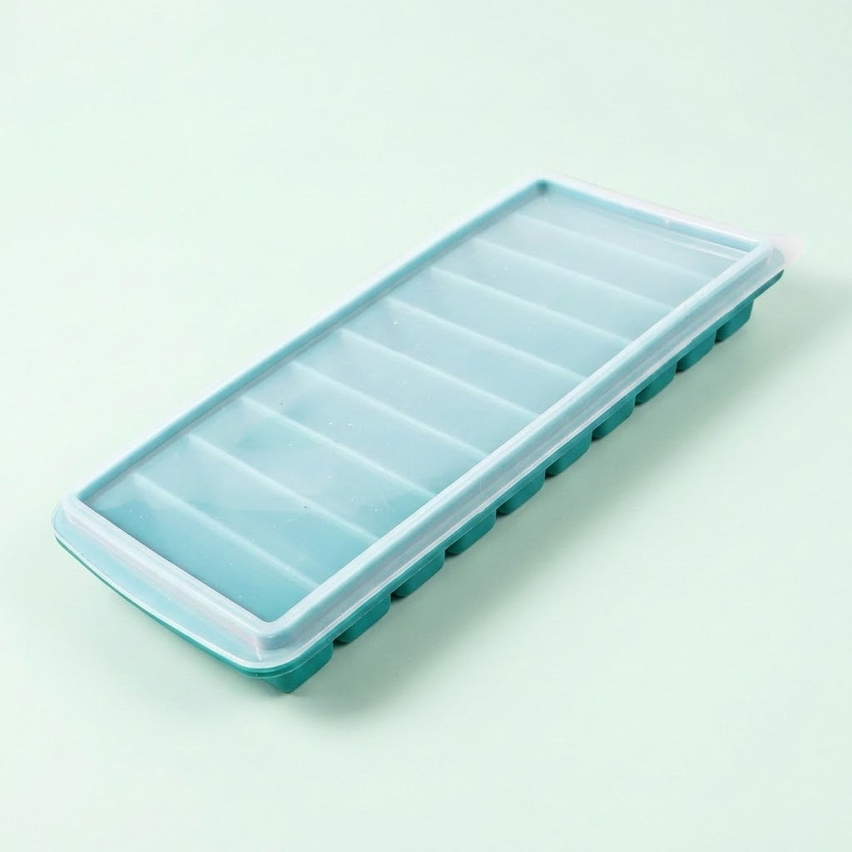 A rectangular silicone ice cube tray with eight compartments, featuring a translucent light blue lid and a teal green base, shown on a solid pale mint green background.
