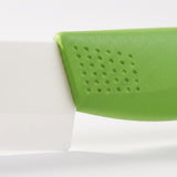 A close-up shows circular dimples on a green knife handle where it meets a white blade against a pale background.