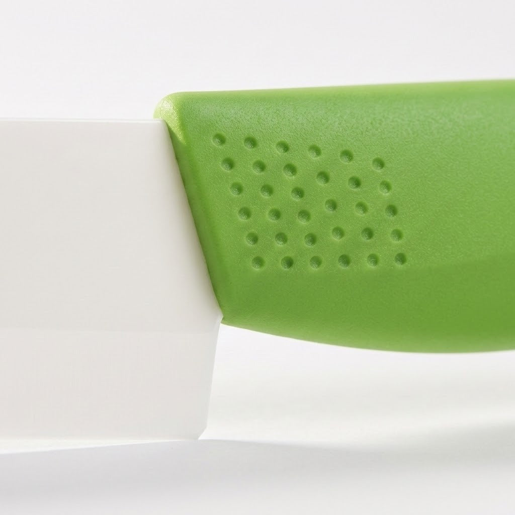 A close-up shows circular dimples on a green knife handle where it meets a white blade against a pale background.